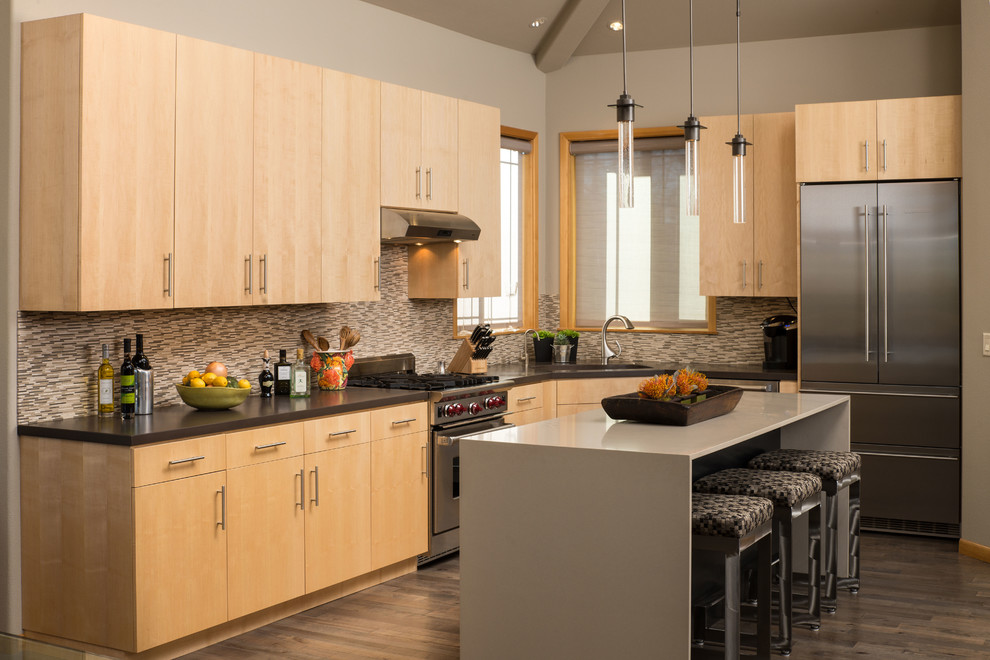 Foto på ett funkis grå l-kök, med släta luckor, skåp i ljust trä, flerfärgad stänkskydd, stänkskydd i stickkakel, rostfria vitvaror, mörkt trägolv och en köksö