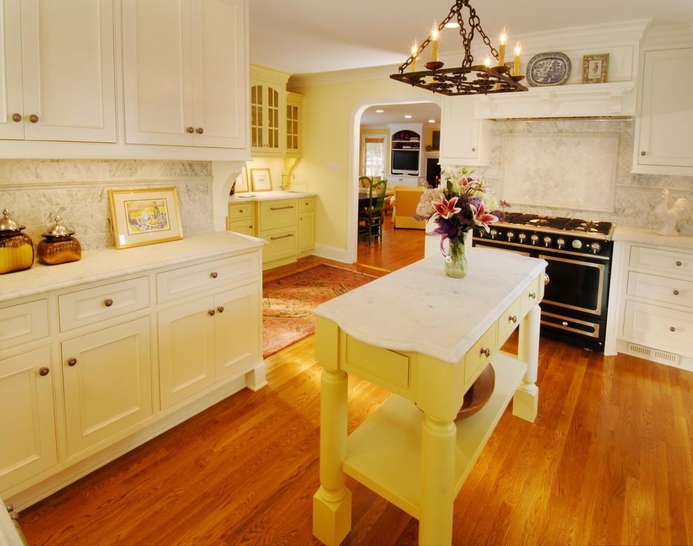 Klassische Küche mit Kassettenfronten, weißen Schränken, Küchenrückwand in Weiß, schwarzen Elektrogeräten und Mauersteinen in Charlotte