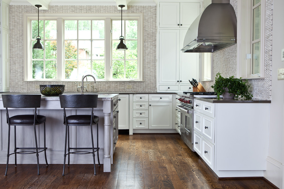 Cette photo montre une cuisine chic avec un placard avec porte à panneau encastré, des portes de placard blanches, une crédence en mosaïque, un électroménager en acier inoxydable et une crédence grise.