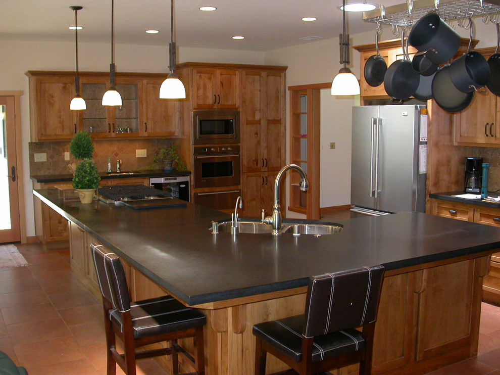 Bild på ett stort amerikanskt kök, med en undermonterad diskho, släta luckor, skåp i ljust trä, granitbänkskiva, beige stänkskydd, stänkskydd i keramik, rostfria vitvaror och klinkergolv i porslin