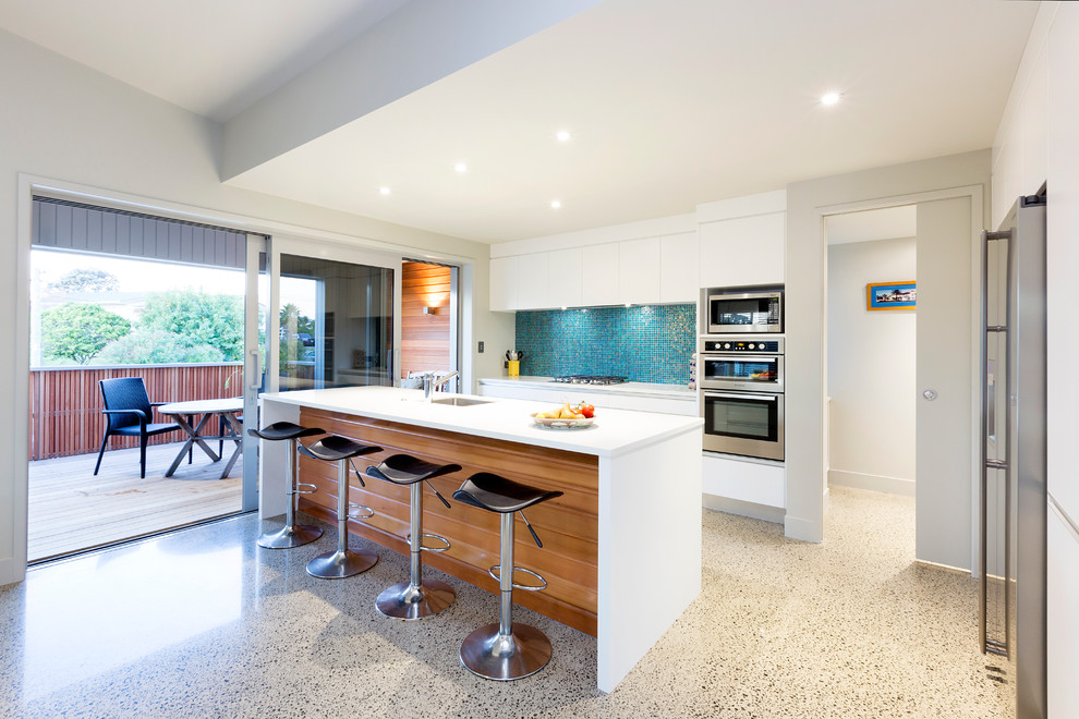 Idéer för ett modernt kök, med en undermonterad diskho, blått stänkskydd, stänkskydd i mosaik, rostfria vitvaror och en köksö