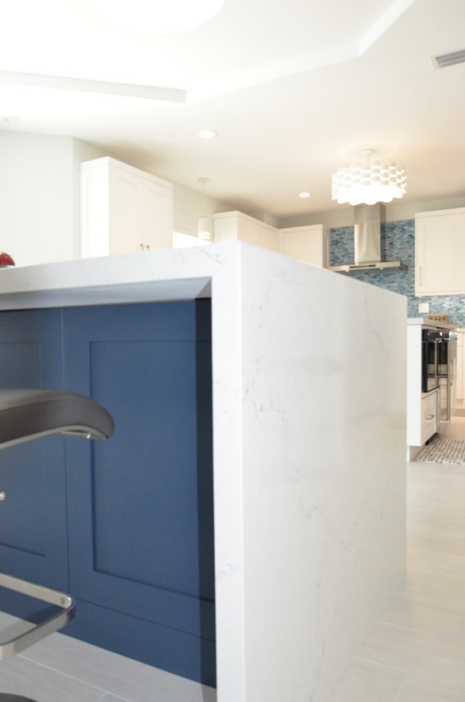 Mid-sized minimalist u-shaped porcelain tile and white floor eat-in kitchen photo in Miami with an undermount sink, shaker cabinets, white cabinets, quartzite countertops, blue backsplash, mosaic tile backsplash, stainless steel appliances, an island and white countertops