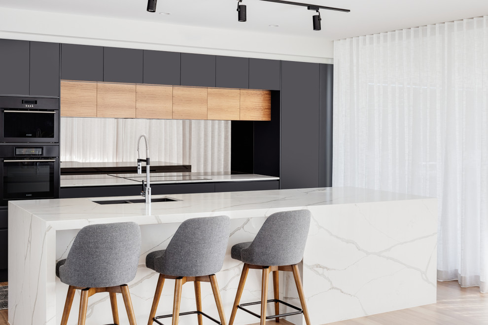 Offene, Zweizeilige, Mittelgroße Moderne Küche mit Unterbauwaschbecken, Quarzwerkstein-Arbeitsplatte, Glasrückwand, braunem Holzboden, Kücheninsel und weißer Arbeitsplatte in Brisbane