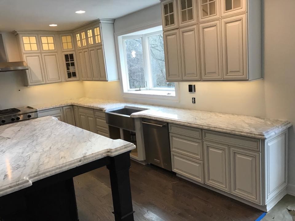 This is an example of a large traditional l-shaped open plan kitchen in Atlanta with a submerged sink, raised-panel cabinets, white cabinets, marble worktops, stainless steel appliances, dark hardwood flooring, an island and brown floors.