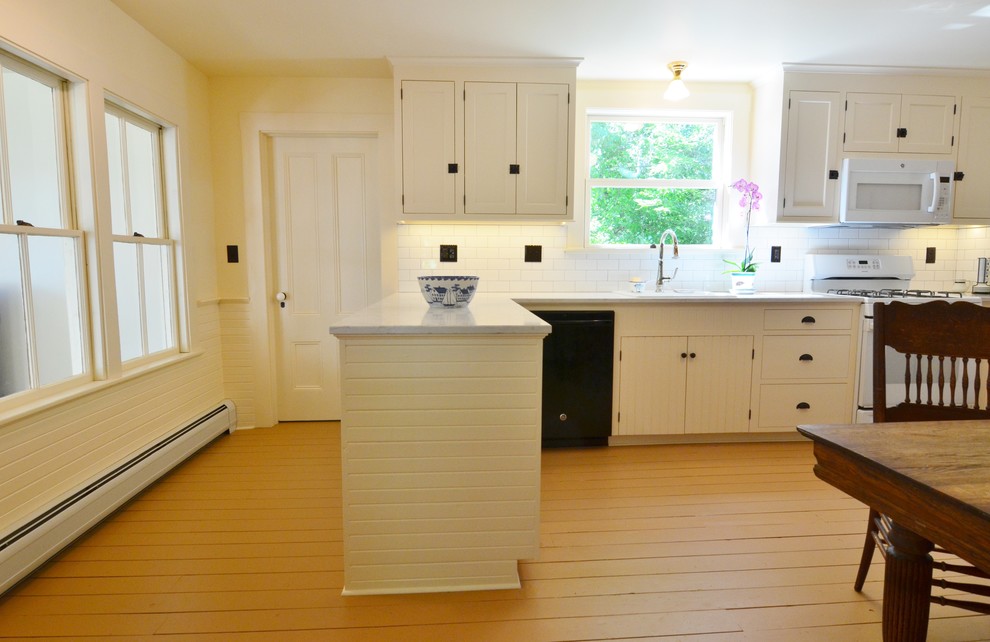 ポートランド(メイン)にある高級な中くらいなトラディショナルスタイルのおしゃれなキッチン (シングルシンク、シェーカースタイル扉のキャビネット、白いキャビネット、クオーツストーンカウンター、白いキッチンパネル、サブウェイタイルのキッチンパネル、白い調理設備、塗装フローリング、茶色い床、グレーのキッチンカウンター) の写真