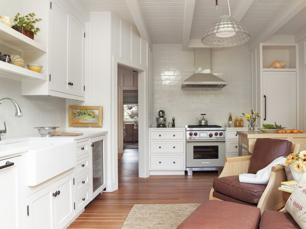 Klassische Küche mit Landhausspüle, Schrankfronten im Shaker-Stil, weißen Schränken, Küchenrückwand in Weiß, Küchengeräten aus Edelstahl und braunem Holzboden in San Francisco