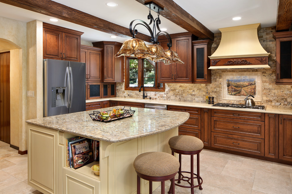 Example of a tuscan kitchen design in San Francisco with an undermount sink, raised-panel cabinets, dark wood cabinets, beige backsplash, stainless steel appliances and an island