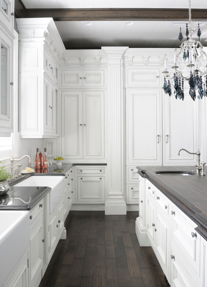 Klassische Küche in U-Form mit Schrankfronten mit vertiefter Füllung, weißen Schränken, Elektrogeräten mit Frontblende, dunklem Holzboden und Kücheninsel