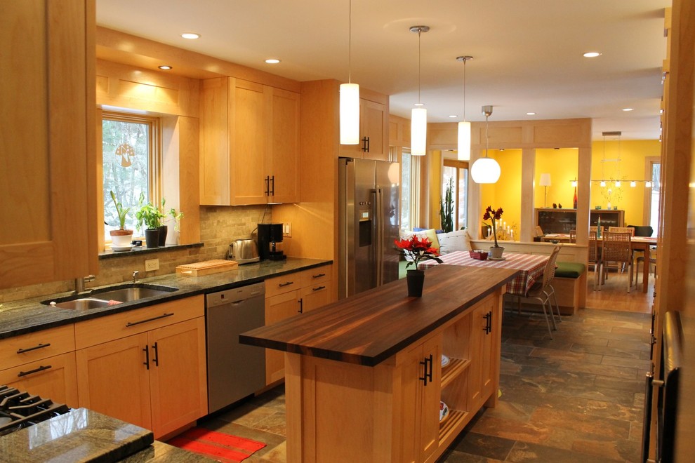 Foto på ett stort funkis kök och matrum, med en undermonterad diskho, släta luckor, skåp i ljust trä, granitbänkskiva, beige stänkskydd, stänkskydd i stenkakel, rostfria vitvaror, klinkergolv i porslin och en köksö