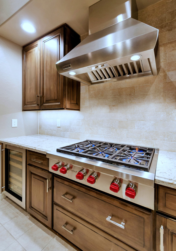 Inspiration for a large transitional l-shaped ceramic tile and white floor open concept kitchen remodel in Phoenix with an undermount sink, raised-panel cabinets, medium tone wood cabinets, solid surface countertops, white backsplash, stainless steel appliances and an island