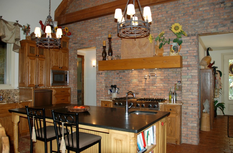 Esempio di una grande cucina con lavello da incasso, ante a filo, ante in legno scuro, top in granito, paraspruzzi rosso, elettrodomestici in acciaio inossidabile e pavimento in mattoni
