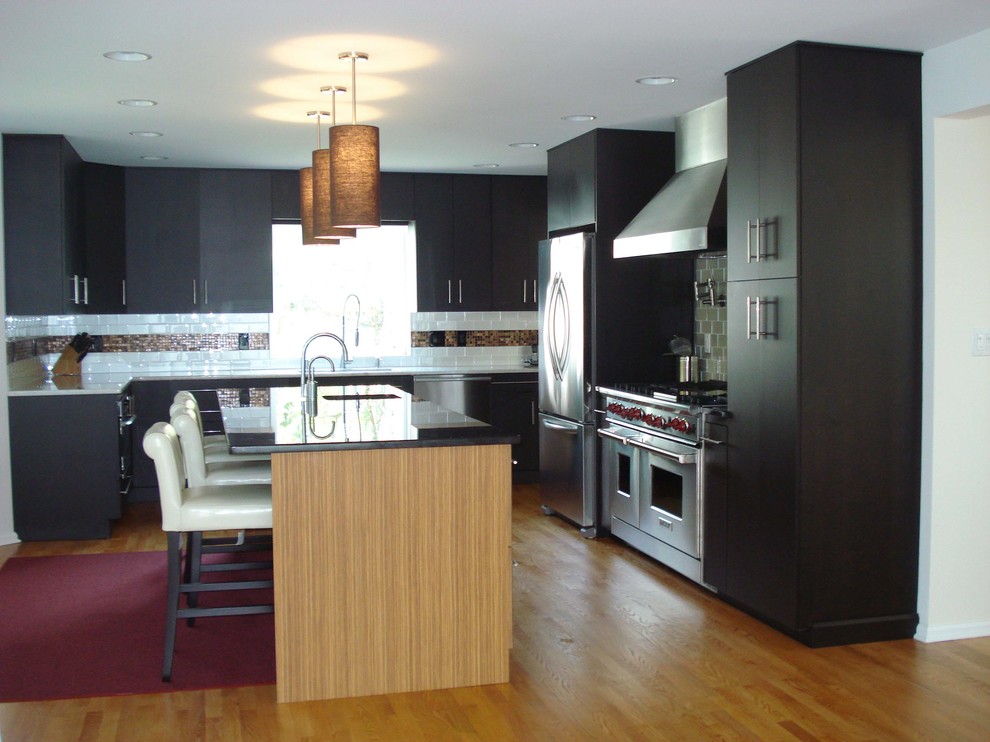 Moderne Küche mit schwarzen Schränken, Küchenrückwand in Weiß, Rückwand aus Keramikfliesen, Küchengeräten aus Edelstahl, hellem Holzboden und Kücheninsel in Philadelphia