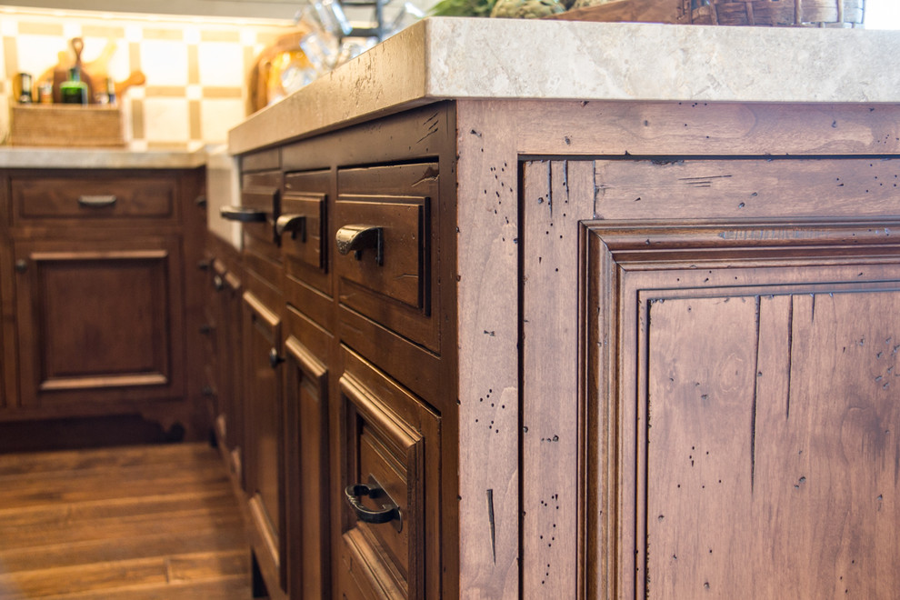 Bild på ett rustikt u-kök, med en rustik diskho, luckor med infälld panel, beige skåp, beige stänkskydd, stänkskydd i keramik, integrerade vitvaror, mörkt trägolv, en köksö och brunt golv