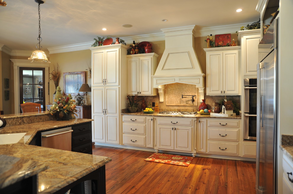 Inredning av ett klassiskt stort kök, med en undermonterad diskho, luckor med upphöjd panel, vita skåp, granitbänkskiva, brunt stänkskydd, stänkskydd i stenkakel, rostfria vitvaror, mellanmörkt trägolv, en köksö och brunt golv
