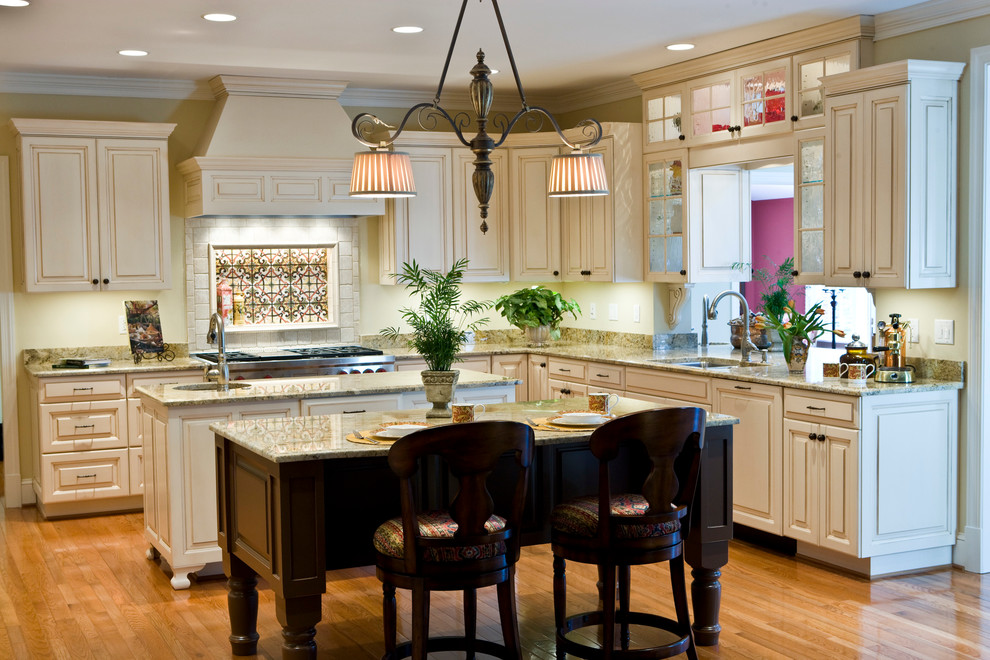Eat-in kitchen - huge traditional medium tone wood floor eat-in kitchen idea in Richmond with a double-bowl sink, raised-panel cabinets, beige cabinets, granite countertops, beige backsplash, terra-cotta backsplash, paneled appliances and two islands