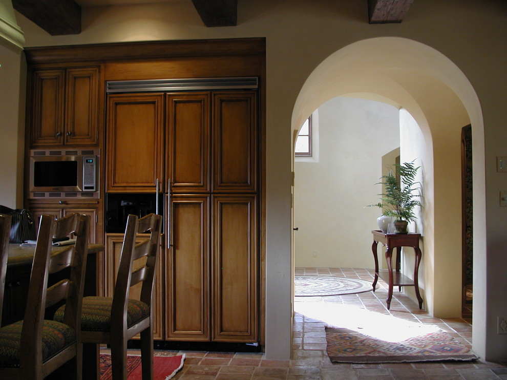 Foto på ett stort medelhavsstil kök, med luckor med infälld panel, skåp i mellenmörkt trä, integrerade vitvaror och klinkergolv i terrakotta