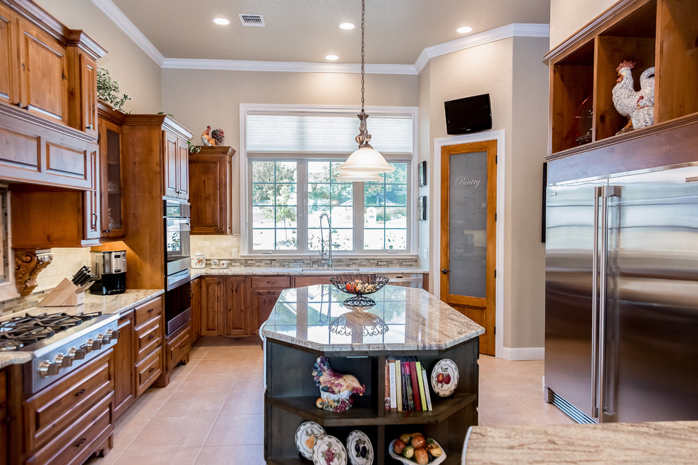Inspiration for a mid-sized craftsman l-shaped travertine floor and brown floor enclosed kitchen remodel in Austin with an undermount sink, raised-panel cabinets, dark wood cabinets, granite countertops, beige backsplash, porcelain backsplash, stainless steel appliances and an island