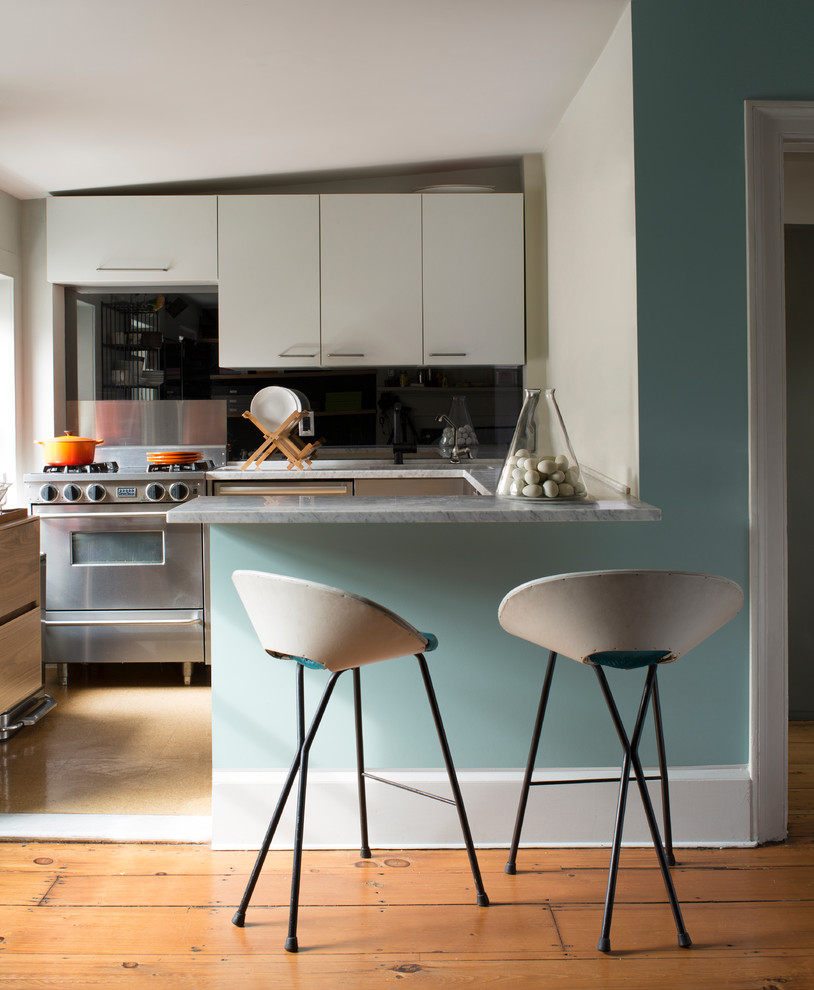 Eat-in kitchen photo in New York with an island and black countertops