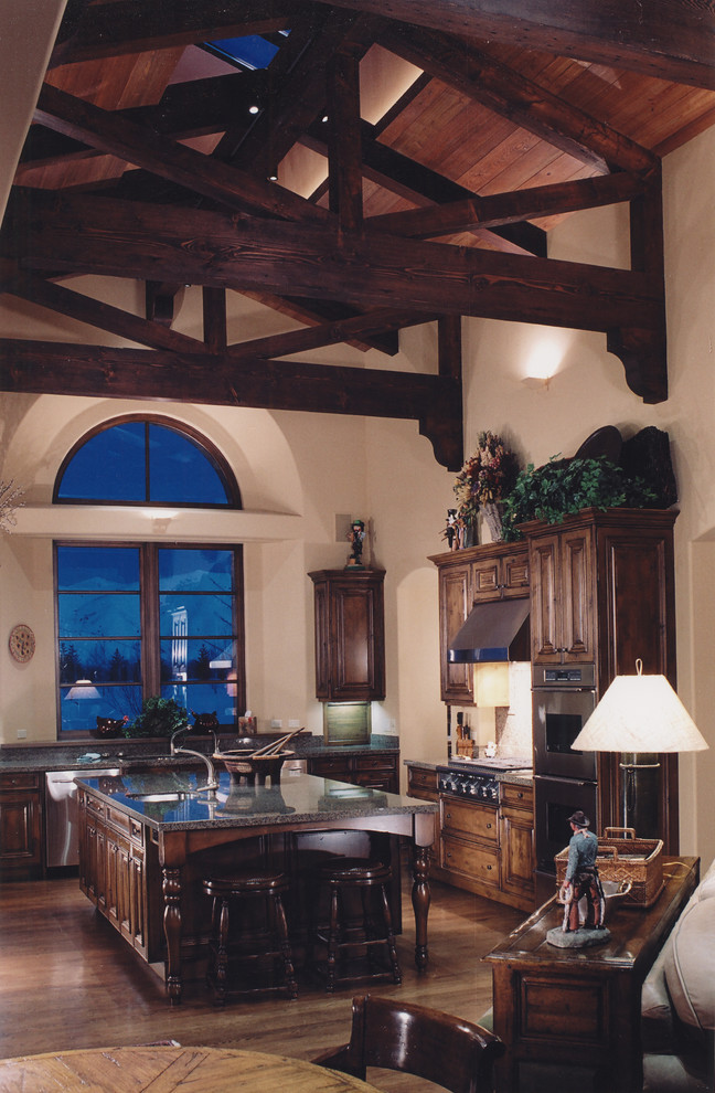 Exemple d'une grande cuisine ouverte craftsman en U et bois foncé avec un plan de travail en granite, un électroménager en acier inoxydable, un sol en bois brun et îlot.
