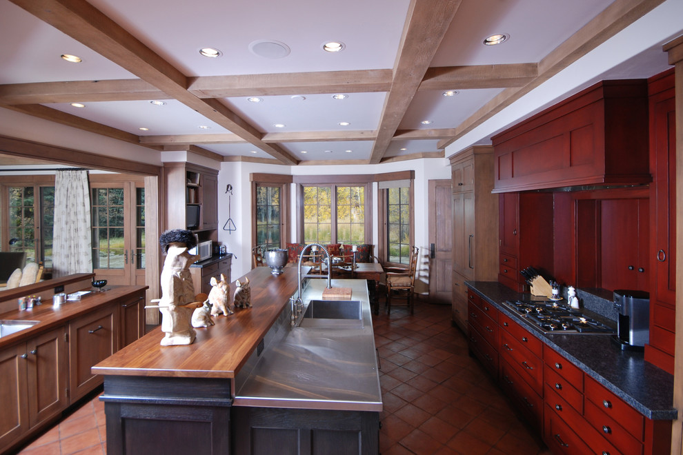 Inredning av ett amerikanskt stort kök, med röda skåp, bänkskiva i rostfritt stål, klinkergolv i terrakotta och en köksö