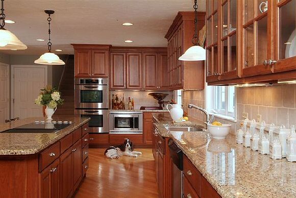 Exempel på ett stort modernt kök, med en enkel diskho, luckor med infälld panel, bruna skåp, granitbänkskiva, grått stänkskydd, stänkskydd i stenkakel, rostfria vitvaror, ljust trägolv och en köksö