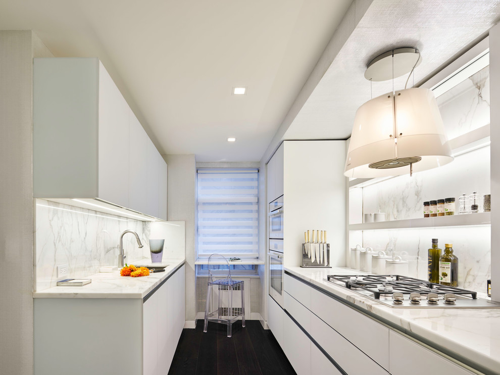 Zweizeilige Moderne Küche mit Unterbauwaschbecken, flächenbündigen Schrankfronten, weißen Schränken, Marmor-Arbeitsplatte, Rückwand aus Marmor und Elektrogeräten mit Frontblende in New York