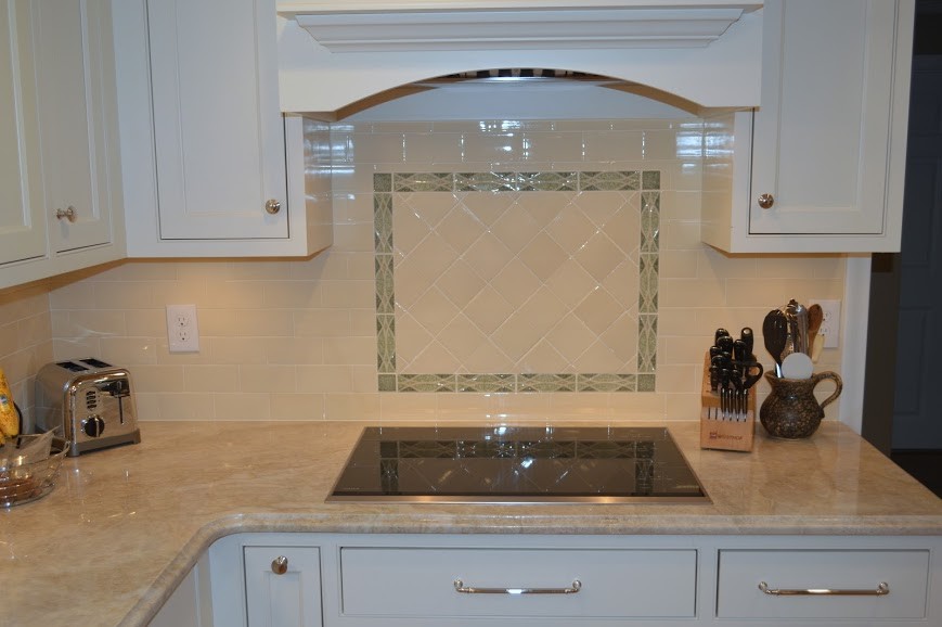 Klassisk inredning av ett kök, med luckor med profilerade fronter, vita skåp, granitbänkskiva, beige stänkskydd och stänkskydd i glaskakel