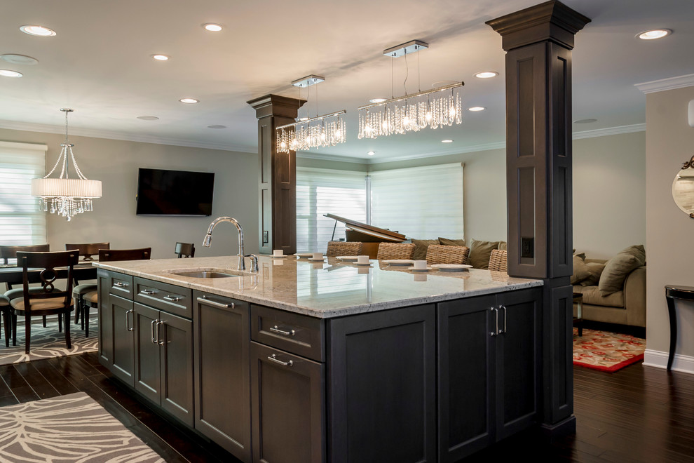 This is an example of an expansive classic u-shaped open plan kitchen in Chicago with a submerged sink, recessed-panel cabinets, grey cabinets, granite worktops, stainless steel appliances, laminate floors, an island, brown floors and white worktops.