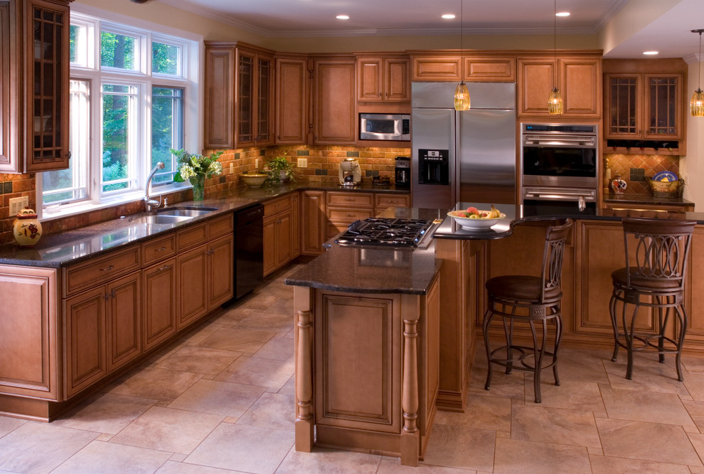Foto de cocina clásica con armarios con paneles con relieve, puertas de armario marrones, salpicadero multicolor y electrodomésticos de acero inoxidable