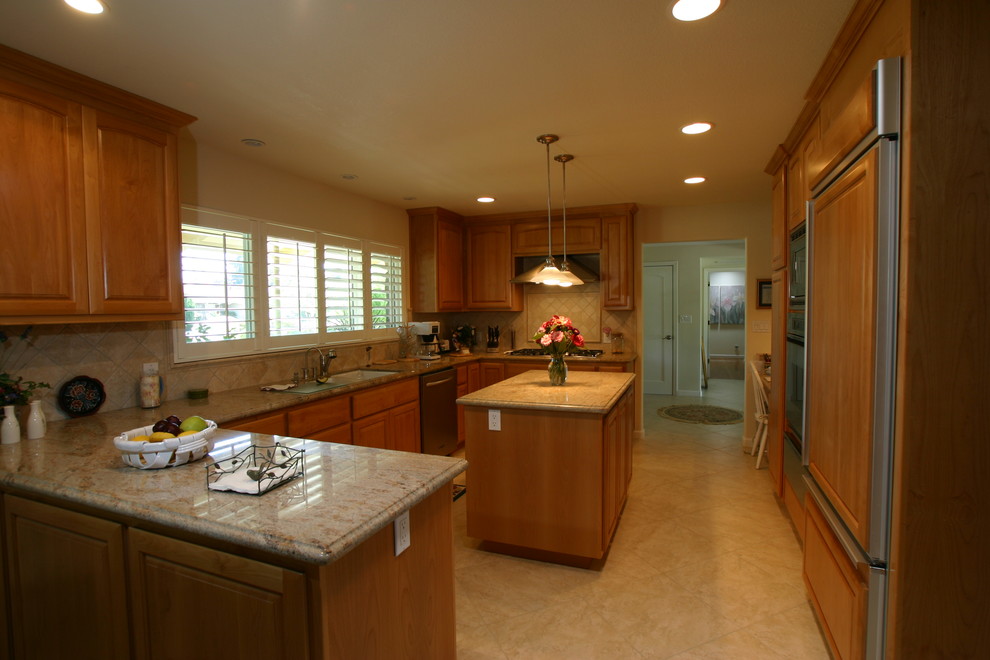 Exempel på ett klassiskt kök, med en undermonterad diskho, luckor med upphöjd panel, skåp i ljust trä, granitbänkskiva, grönt stänkskydd, stänkskydd i stenkakel och integrerade vitvaror