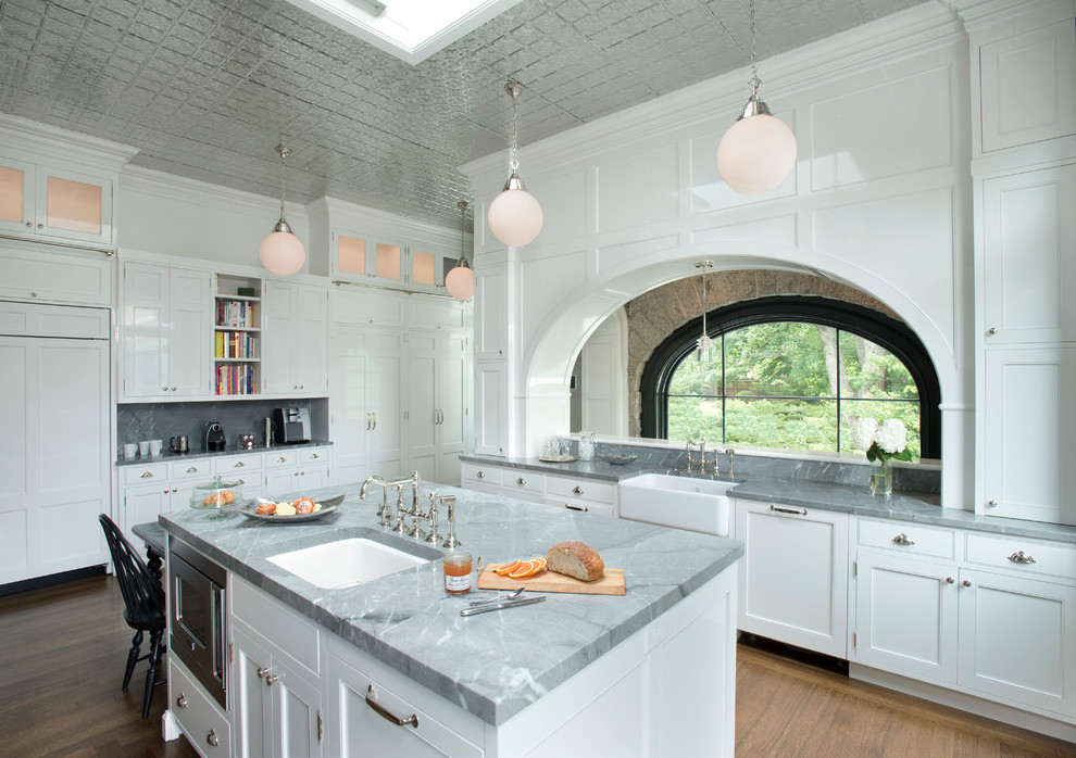 Mittelgroße Klassische Küche mit Landhausspüle, weißen Schränken, Elektrogeräten mit Frontblende, braunem Holzboden, Kücheninsel und Kassettenfronten in Boston