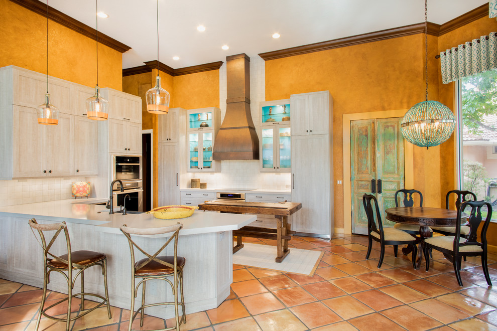 Inspiration for a mid-sized southwestern u-shaped terra-cotta tile and orange floor eat-in kitchen remodel in Miami with shaker cabinets, ceramic backsplash, stainless steel appliances, an island, a farmhouse sink, white cabinets, white backsplash and white countertops