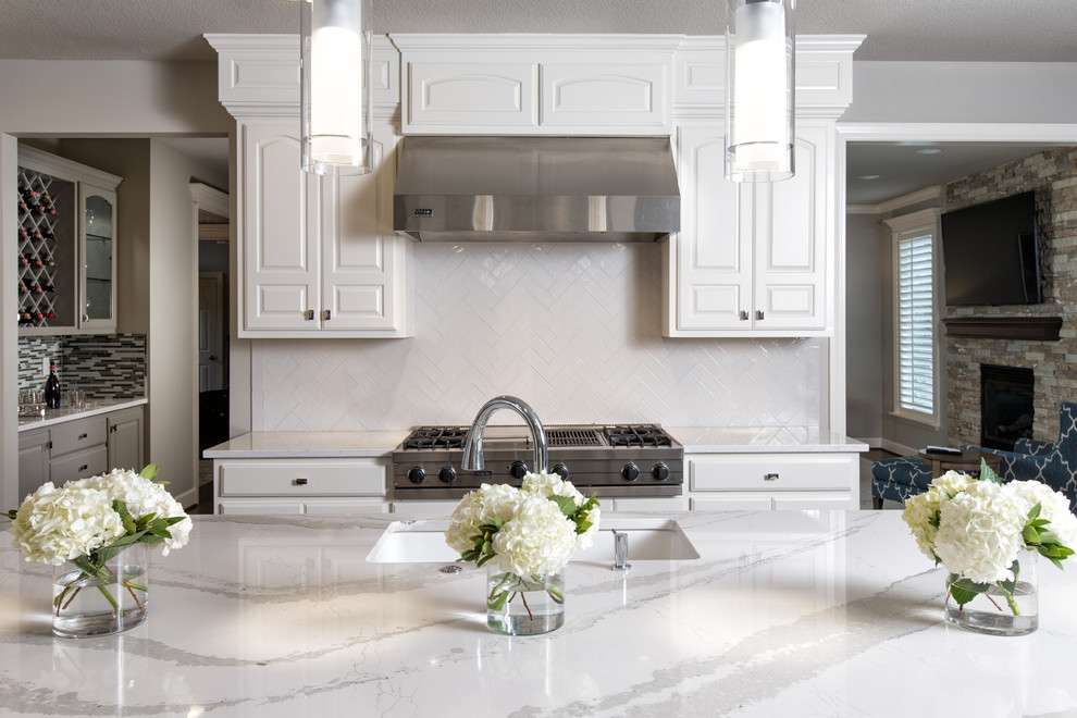 Example of a large transitional l-shaped dark wood floor eat-in kitchen design in Kansas City with an undermount sink, raised-panel cabinets, white cabinets, quartz countertops, white backsplash, subway tile backsplash, stainless steel appliances and an island