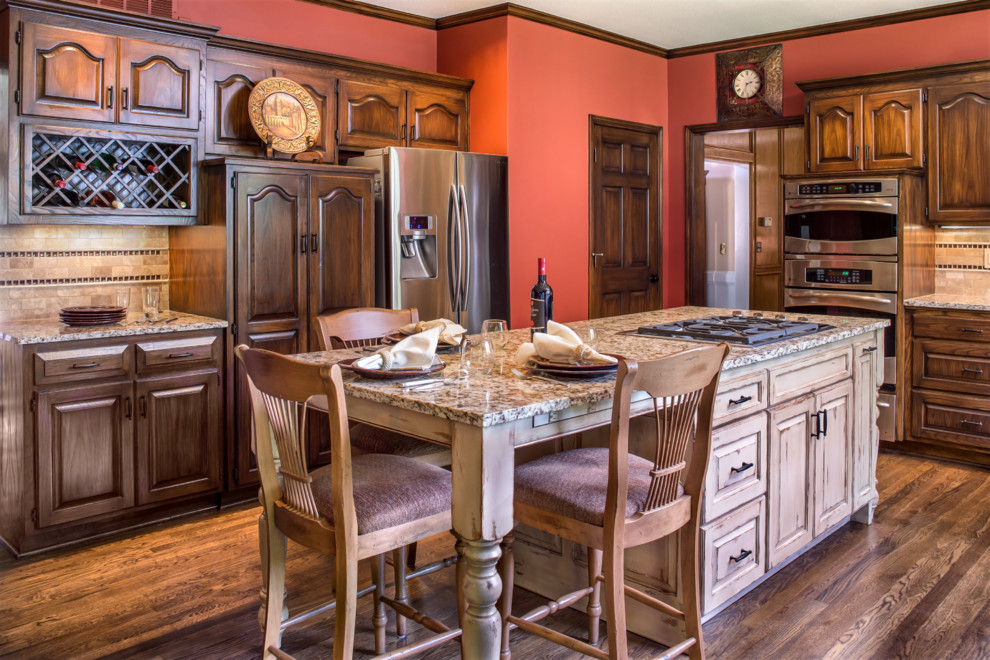Bild på ett mellanstort vintage kök, med granitbänkskiva, beige stänkskydd, rostfria vitvaror, mellanmörkt trägolv, en köksö, en dubbel diskho, luckor med profilerade fronter, skåp i slitet trä och stänkskydd i stenkakel
