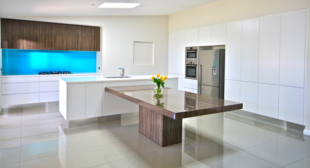 Large minimalist l-shaped porcelain tile eat-in kitchen photo in Sydney with an undermount sink, flat-panel cabinets, white cabinets, quartz countertops, blue backsplash, glass sheet backsplash, stainless steel appliances and two islands