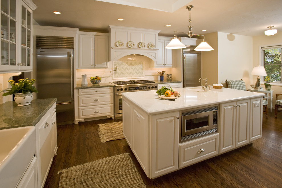 Example of a classic enclosed kitchen design in San Francisco with raised-panel cabinets, stainless steel appliances, a farmhouse sink, white cabinets and multicolored backsplash