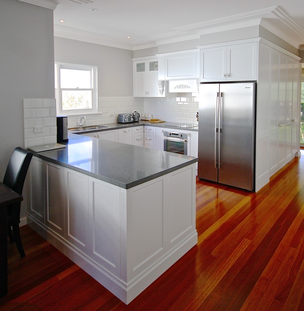 Mid-sized transitional u-shaped medium tone wood floor eat-in kitchen photo in Sydney with a double-bowl sink, recessed-panel cabinets, white cabinets, quartz countertops, white backsplash, ceramic backsplash, stainless steel appliances and no island