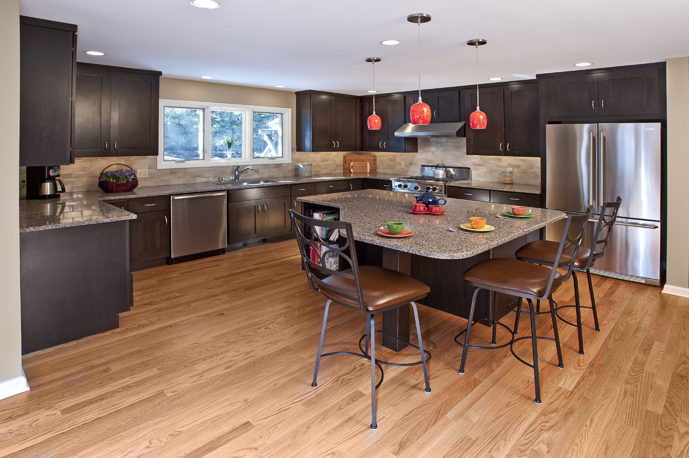 Exempel på ett modernt kök, med en undermonterad diskho, luckor med infälld panel, granitbänkskiva, brunt stänkskydd, ljust trägolv, en köksö och rostfria vitvaror