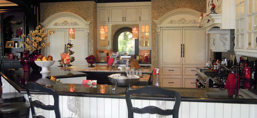 Große Mediterrane Wohnküche in U-Form mit profilierten Schrankfronten, weißen Schränken, Granit-Arbeitsplatte, Küchenrückwand in Beige, Küchengeräten aus Edelstahl, braunem Holzboden, Kücheninsel und braunem Boden in Vancouver