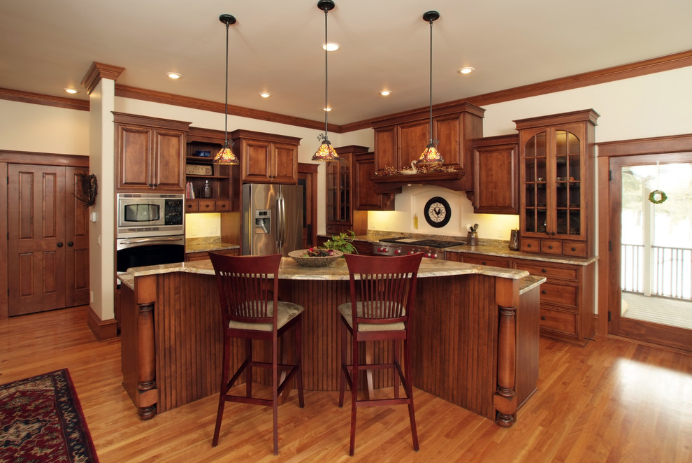Inspiration for a large traditional l-shaped kitchen/diner in Milwaukee with raised-panel cabinets, medium wood cabinets, stainless steel appliances, granite worktops, beige splashback, medium hardwood flooring and an island.