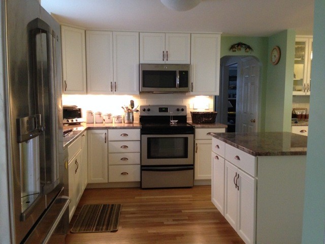 Foto på ett stort vintage kök, med en dubbel diskho, skåp i shakerstil, vita skåp, bänkskiva i kvartsit, rostfria vitvaror, mellanmörkt trägolv och en köksö