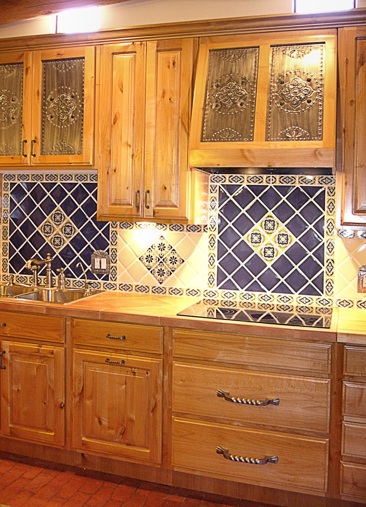 Esempio di una cucina tradizionale di medie dimensioni con lavello da incasso, ante con bugna sagomata, ante in legno scuro, paraspruzzi blu, paraspruzzi con piastrelle in ceramica, elettrodomestici in acciaio inossidabile, pavimento in mattoni e pavimento rosso