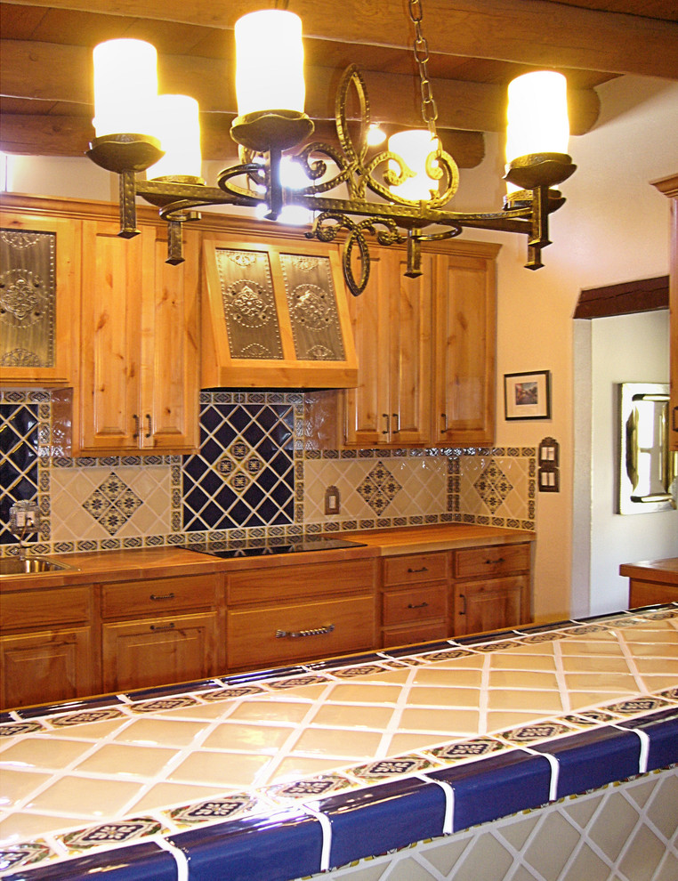 Exemple d'une cuisine ouverte linéaire chic en bois brun de taille moyenne avec un évier posé, un placard avec porte à panneau surélevé, une crédence bleue, une crédence en céramique, un électroménager en acier inoxydable, un sol en brique, îlot et un sol rouge.