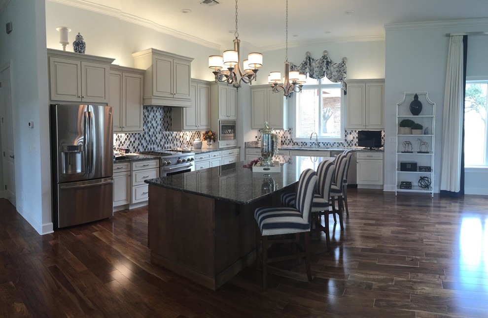 Example of a mid-sized transitional u-shaped dark wood floor and brown floor eat-in kitchen design in Orlando with a double-bowl sink, raised-panel cabinets, yellow cabinets, quartzite countertops, multicolored backsplash, mosaic tile backsplash, stainless steel appliances and an island