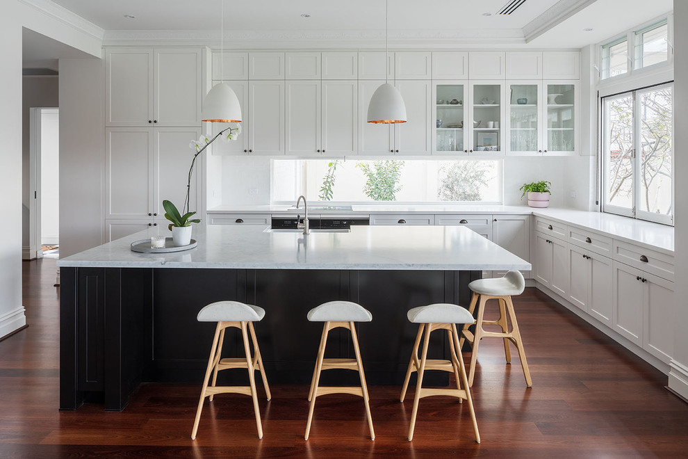 Klassische Küche in L-Form mit Landhausspüle, Schrankfronten im Shaker-Stil, weißen Schränken, Rückwand-Fenster, braunem Holzboden, Kücheninsel und braunem Boden in Perth