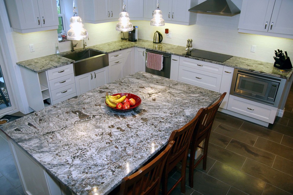 Immagine di una cucina minimalista di medie dimensioni con lavello stile country, ante in stile shaker, ante bianche, top in granito, paraspruzzi bianco, paraspruzzi con piastrelle di vetro, elettrodomestici in acciaio inossidabile, pavimento in ardesia e pavimento grigio