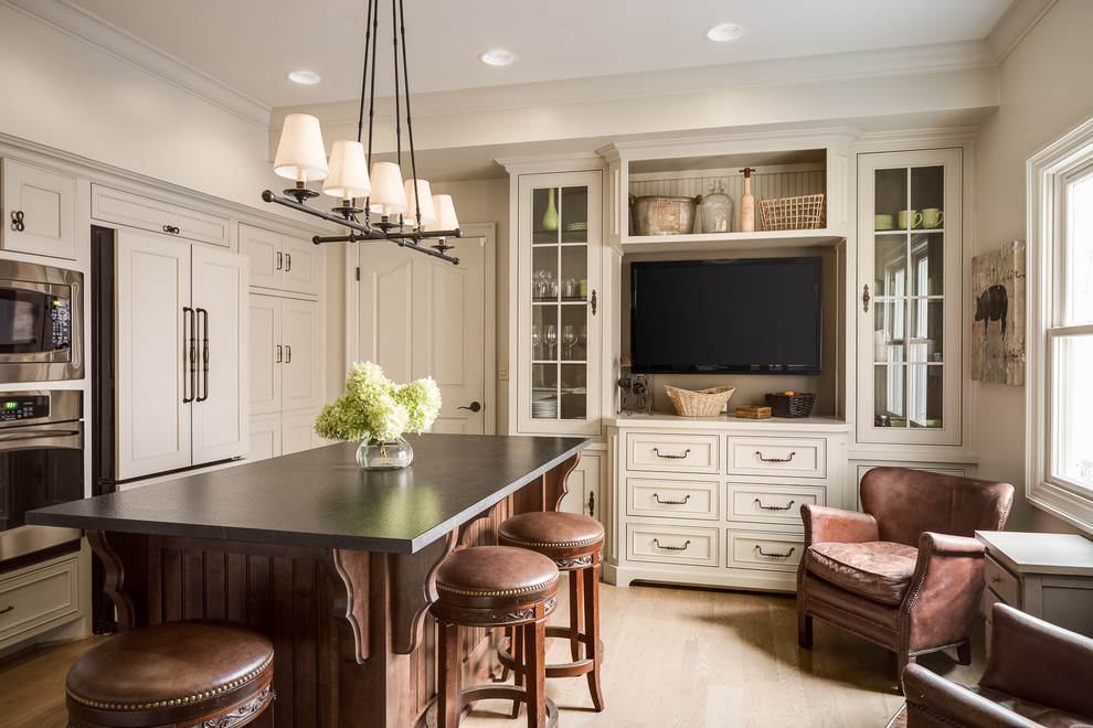 Example of a classic l-shaped light wood floor and beige floor eat-in kitchen design in Boise with recessed-panel cabinets, beige cabinets, paneled appliances, an island and gray countertops