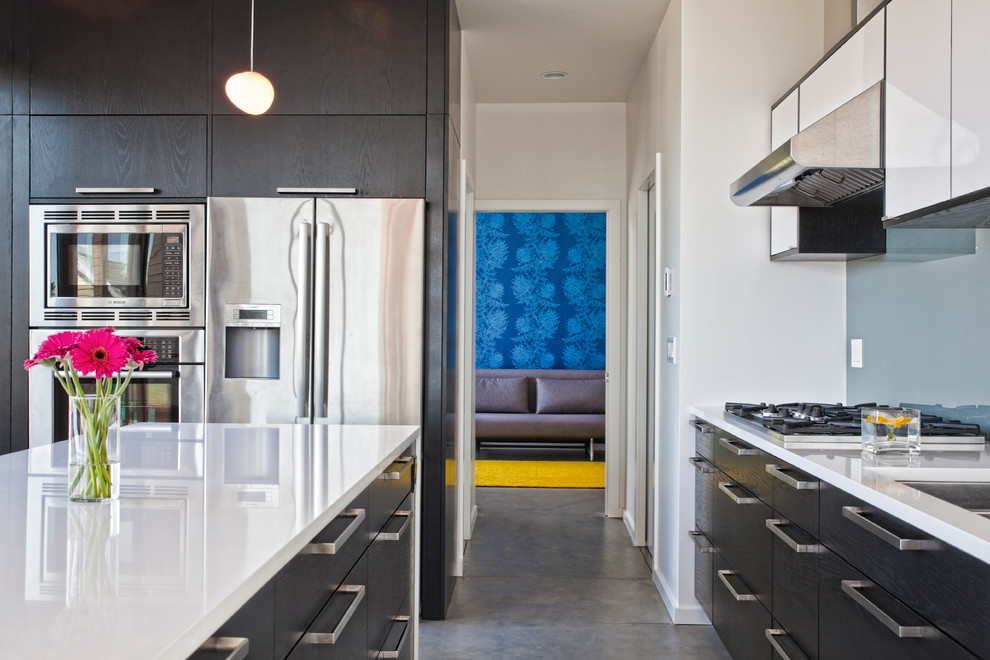 Modelo de cocina contemporánea con armarios con paneles lisos, puertas de armario negras y electrodomésticos de acero inoxidable