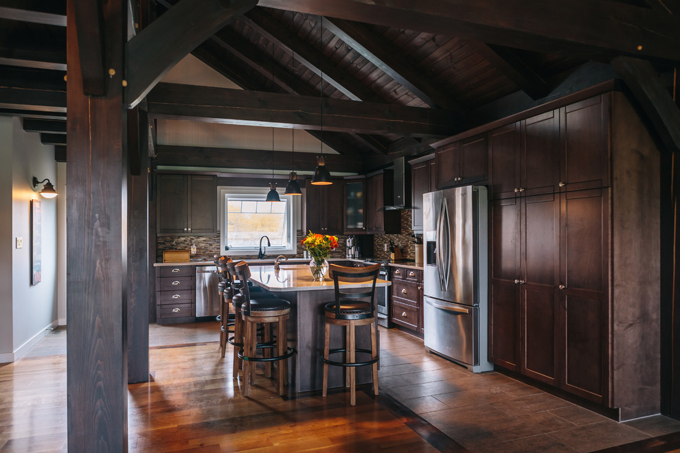 Inspiration for a country l-shaped enclosed kitchen in Other with shaker cabinets, brown cabinets, multi-coloured splashback, matchstick tiled splashback, stainless steel appliances, an island and brown floors.