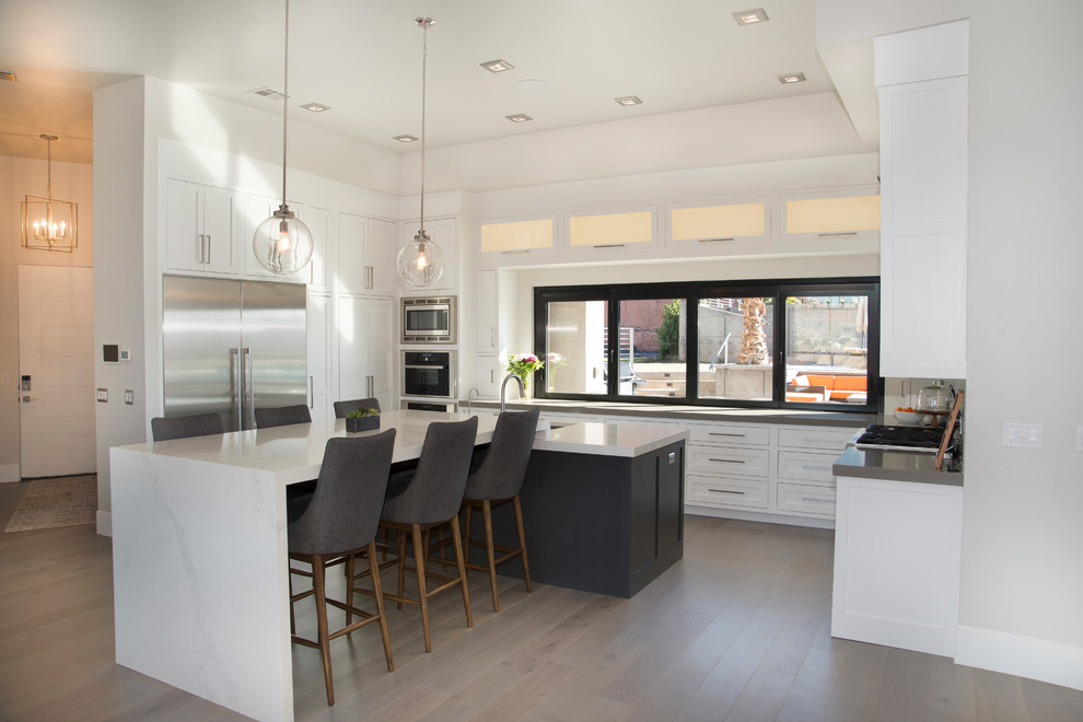 Large trendy u-shaped dark wood floor and brown floor eat-in kitchen photo in Salt Lake City with an undermount sink, shaker cabinets, white cabinets, quartzite countertops, white backsplash, porcelain backsplash, stainless steel appliances, an island and gray countertops